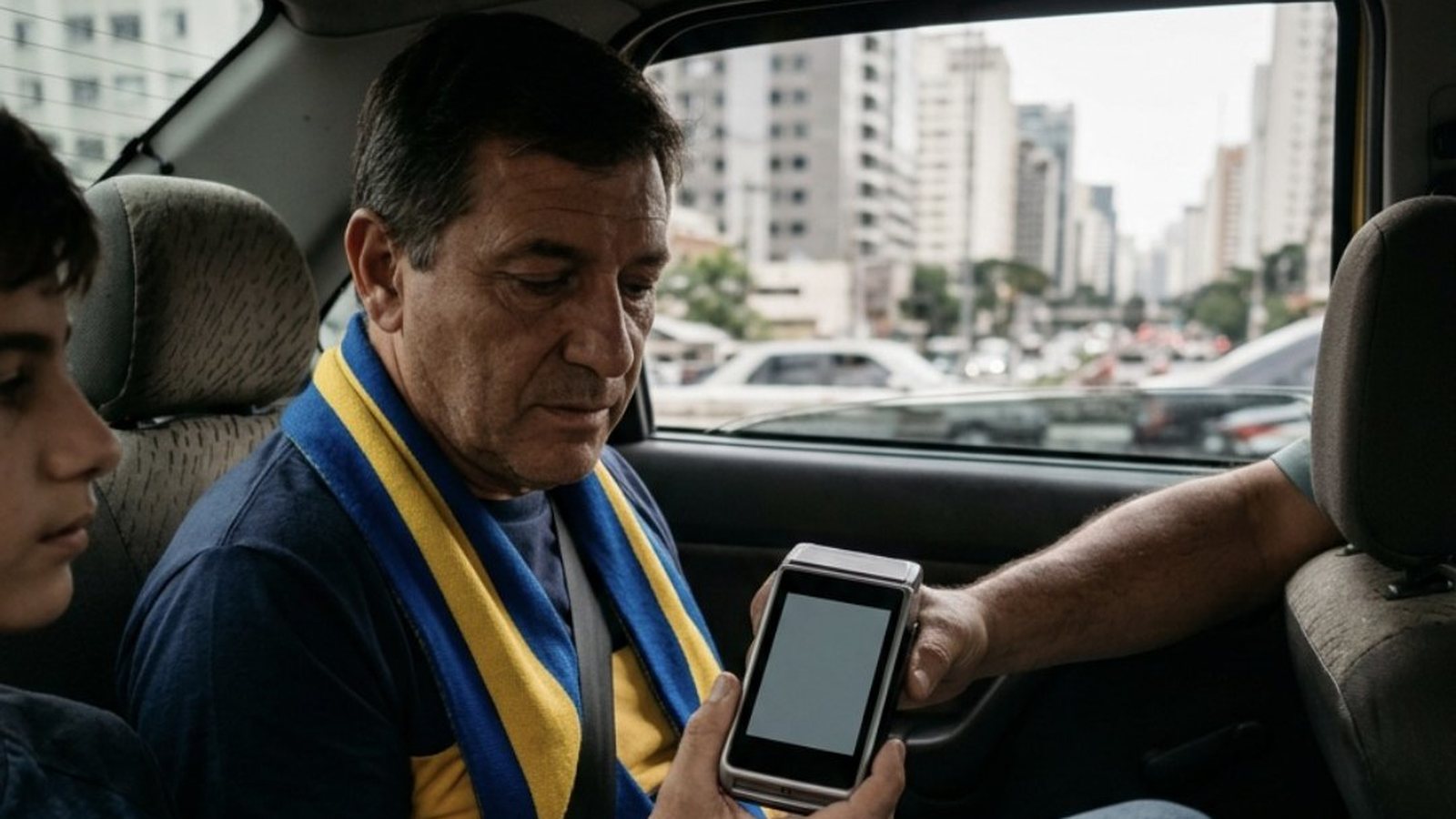 Dentro de um táxi em São Paulo durante o dia, um torcedor argentino de meia-idade com cachecol listrado azul e amarelo, sentado no banco de trás ao lado do filho adolescente, segura a máquina de cartão entregue pelo motorista, cujo braço se estica do banco da frente, com prédios desfocados pela janela
